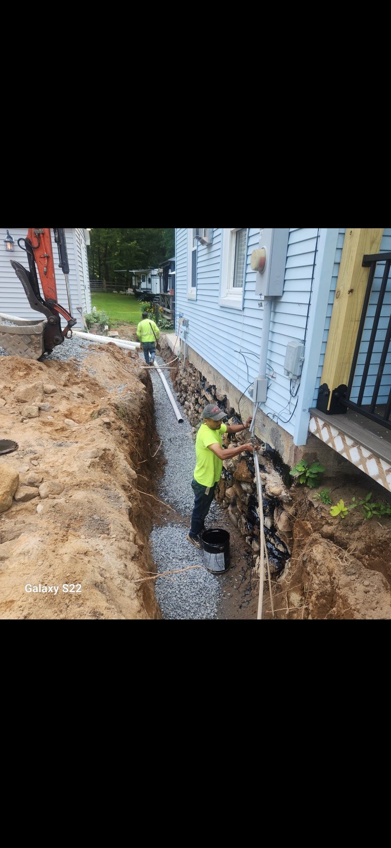 Workers in yellow safety vests excavating a trench between residential houses