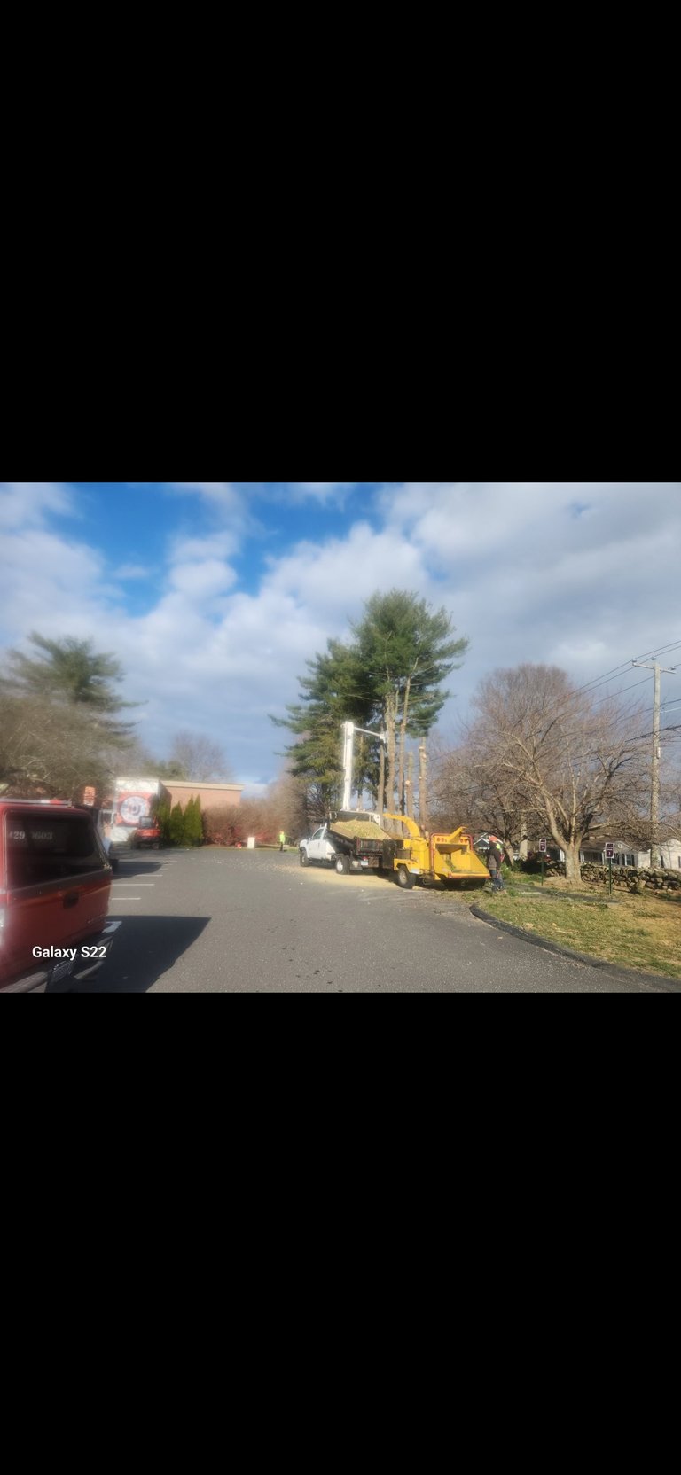 Yellow bucket truck parked on a residential street with bare trees