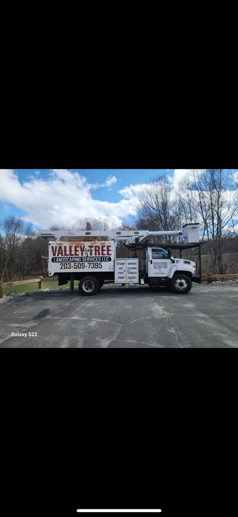 White Valley Tree Landscaping Services truck parked in lot with bare trees and blue sky in background